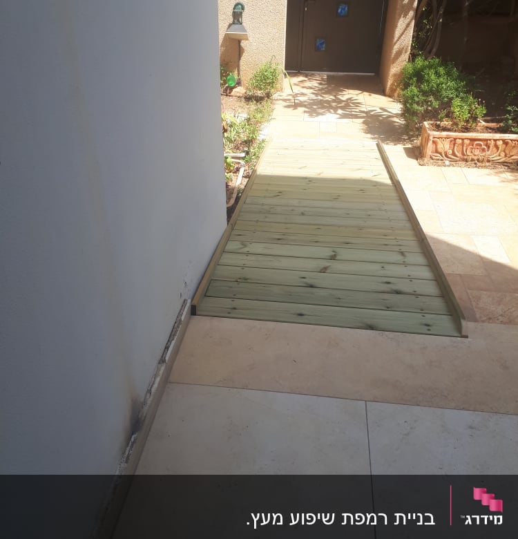 שביל עץ בגינה ליד קיר לבן